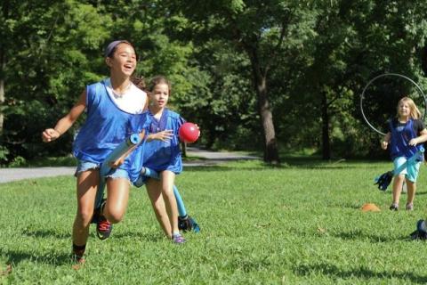 children in blue shirts playing quidditch