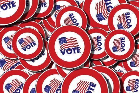 A pile of pins that each show an American flag and the word Vote.