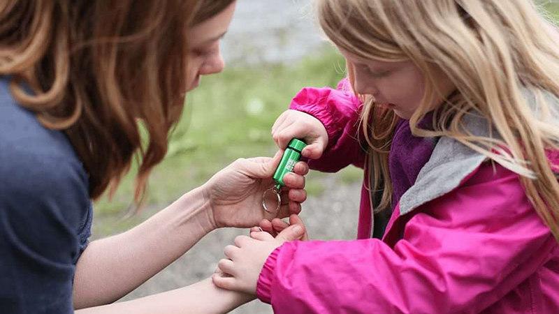 girl and woman looking at a small geocache together