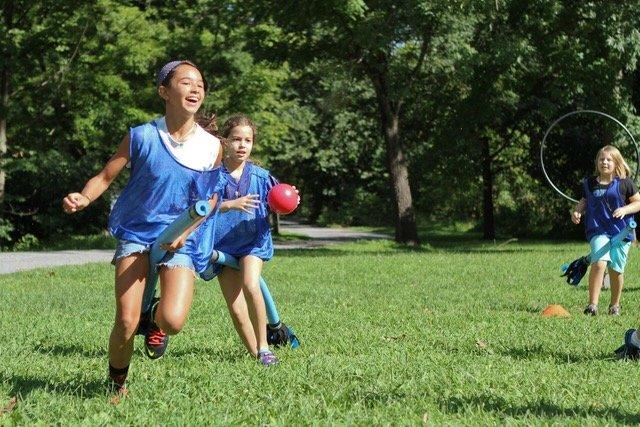 children in blue shirts playing quidditch